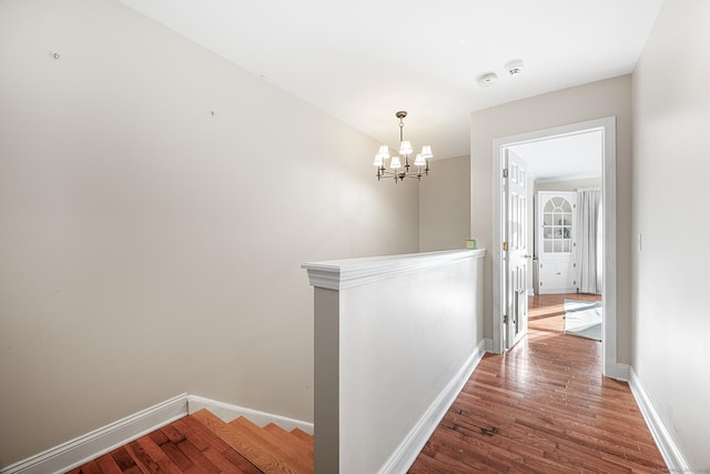 hall with an inviting chandelier and wood-type flooring