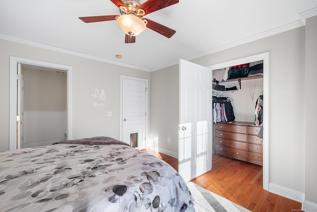 bedroom with crown molding, a walk in closet, light hardwood / wood-style floors, and a closet