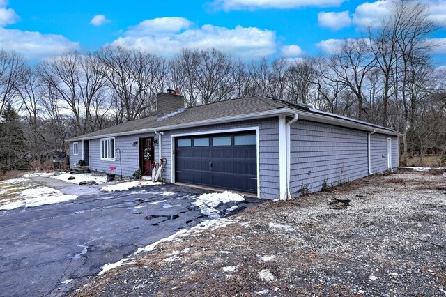 view of front of house featuring a garage, a shingled roof, and a chimney