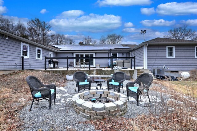 back of property featuring solar panels, cooling unit, a patio area, and a fire pit