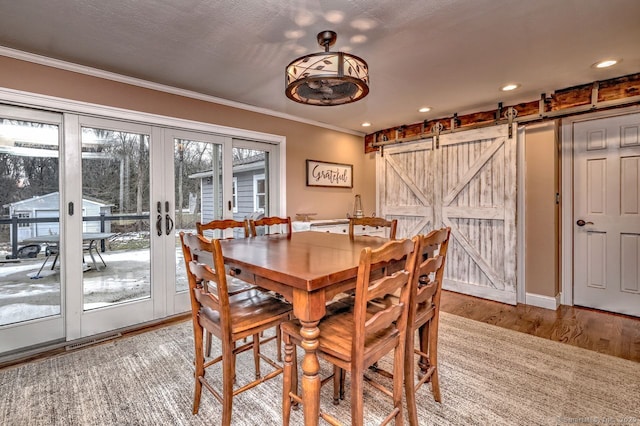 dining room with french doors, ornamental molding, a barn door, and light hardwood / wood-style floors