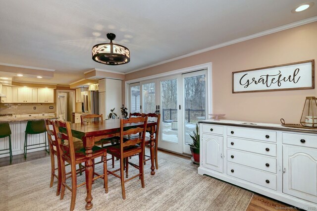 dining area with ornamental molding, light hardwood / wood-style floors, and french doors