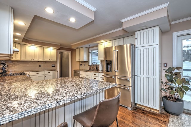 kitchen with stone countertops, white cabinets, ornamental molding, kitchen peninsula, and stainless steel appliances