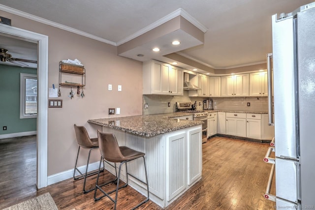 kitchen with white cabinets, stone counters, wall chimney exhaust hood, and appliances with stainless steel finishes