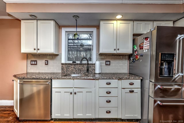 kitchen featuring sink, dark stone countertops, pendant lighting, stainless steel appliances, and white cabinets