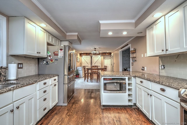 kitchen featuring stainless steel appliances, white cabinets, light stone counters, and kitchen peninsula