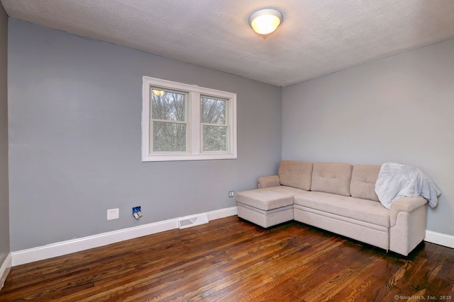 unfurnished living room featuring dark hardwood / wood-style flooring and a textured ceiling