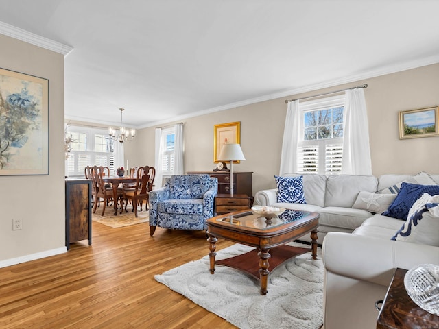 living room featuring crown molding, a notable chandelier, baseboards, and light wood-type flooring