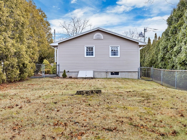 view of side of home with a gate, a fenced backyard, and a yard