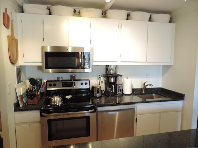 kitchen featuring stainless steel appliances, sink, white cabinets, and dark stone counters