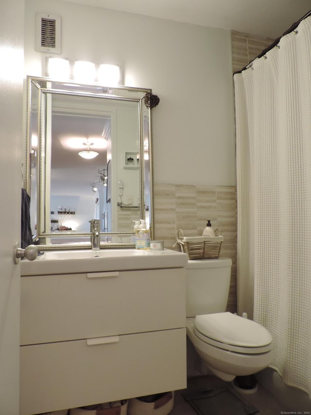 bathroom featuring vanity, tile walls, and toilet