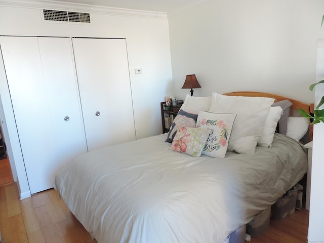 bedroom with crown molding, light hardwood / wood-style flooring, and a closet