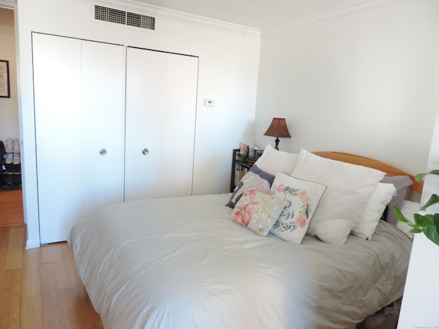 bedroom with a closet, ornamental molding, and light hardwood / wood-style flooring