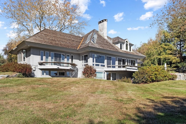 rear view of house with a yard, a chimney, and a sunroom