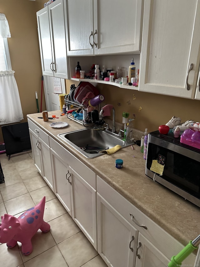 kitchen with white cabinetry, sink, and light tile patterned flooring