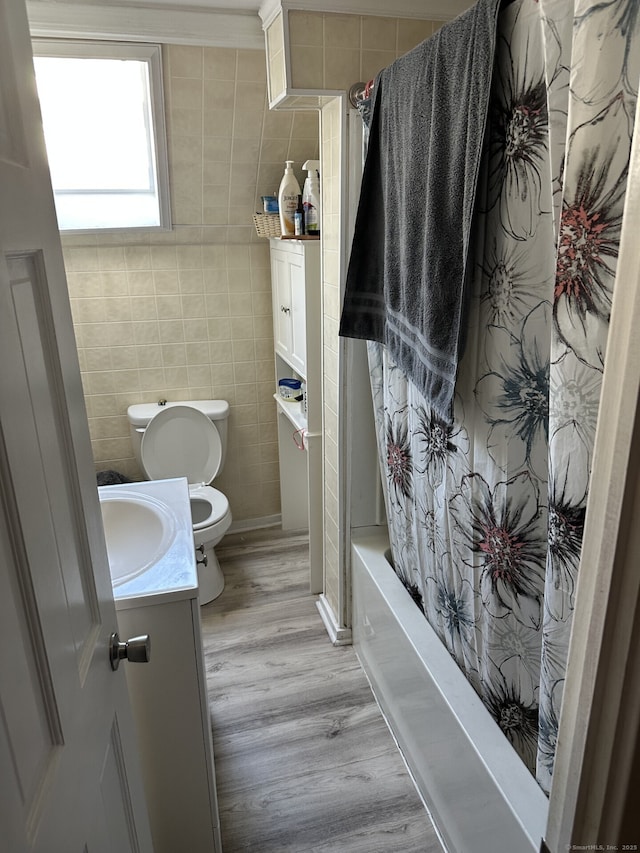 full bathroom with toilet, wood-type flooring, tile walls, vanity, and shower / bath combo