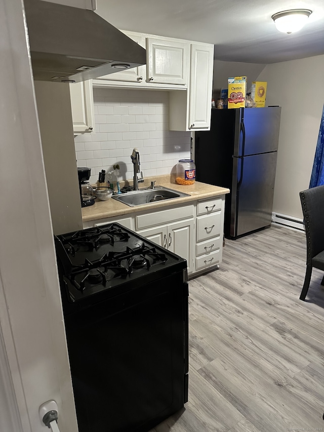 kitchen with black gas range oven, sink, white cabinetry, ventilation hood, and a baseboard radiator