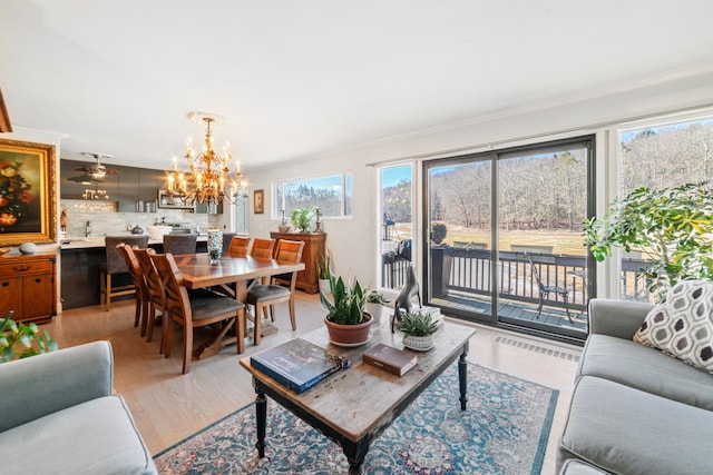 living room with ornamental molding, an inviting chandelier, and light hardwood / wood-style flooring