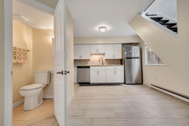 kitchen featuring decorative backsplash, appliances with stainless steel finishes, a sink, white cabinets, and a baseboard heating unit