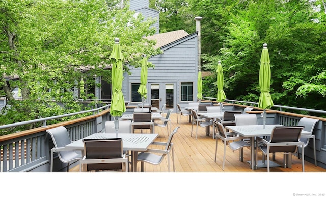 wooden terrace with outdoor dining area and french doors