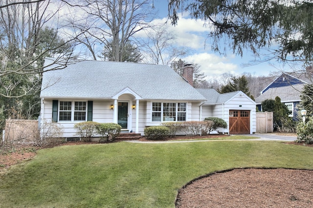 view of front facade with a shingled roof, a chimney, a front yard, and fence