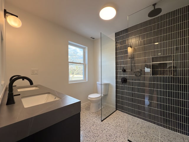 bathroom featuring vanity, tiled shower, and toilet