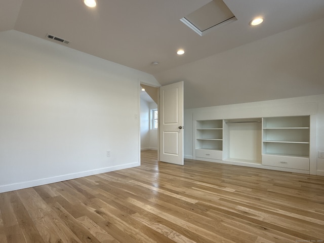 unfurnished bedroom with lofted ceiling, a closet, and light wood-type flooring