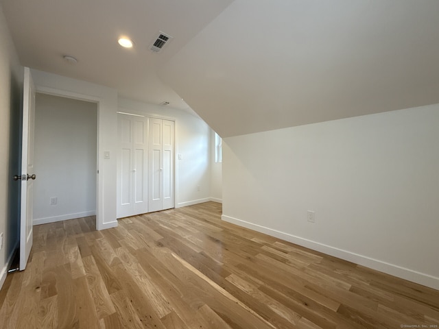 additional living space featuring vaulted ceiling and light hardwood / wood-style floors