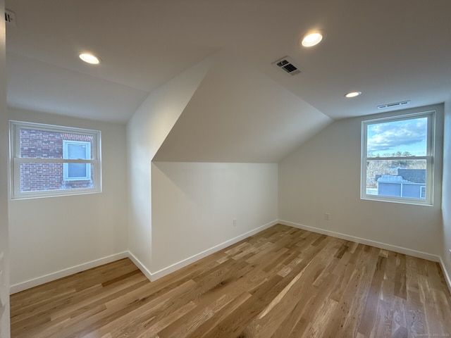 additional living space featuring lofted ceiling and light wood-type flooring