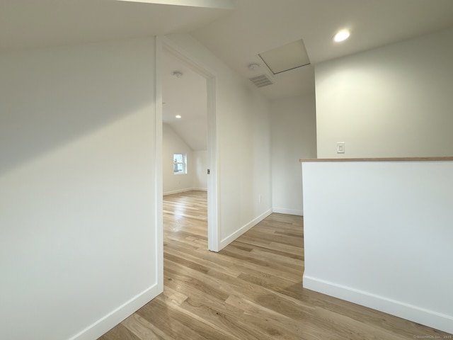 hall with vaulted ceiling and light hardwood / wood-style flooring