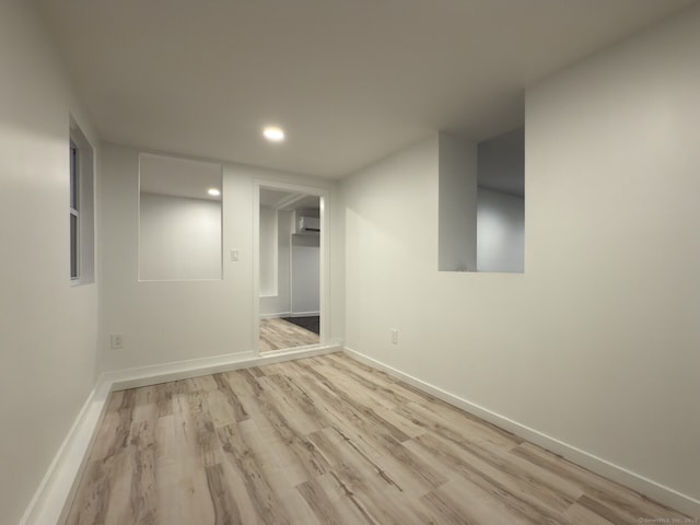 basement featuring a wall unit AC and light wood-type flooring