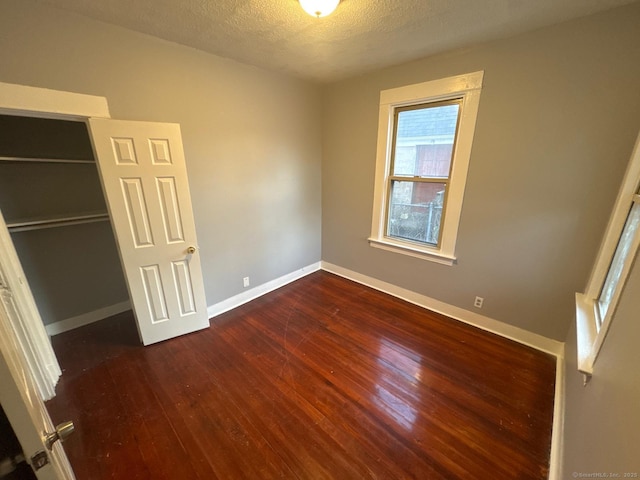 unfurnished bedroom featuring dark hardwood / wood-style flooring, a closet, and a textured ceiling