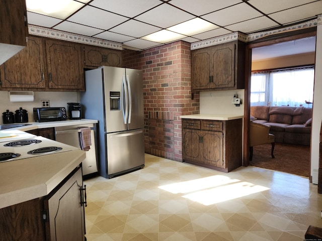 kitchen featuring stainless steel refrigerator with ice dispenser, a paneled ceiling, dark brown cabinetry, and cooktop