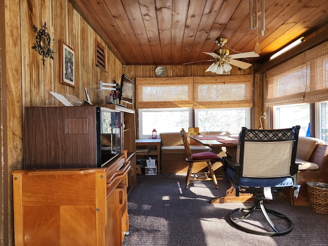 office area with wooden ceiling, a wealth of natural light, dark carpet, and wood walls