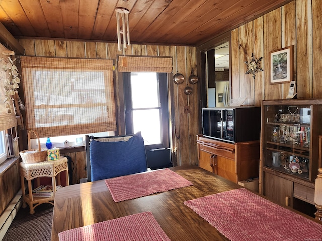 dining area featuring a baseboard radiator, wooden ceiling, wood-type flooring, and wood walls