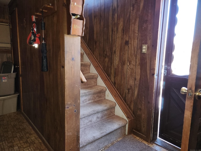 stairway featuring wooden walls