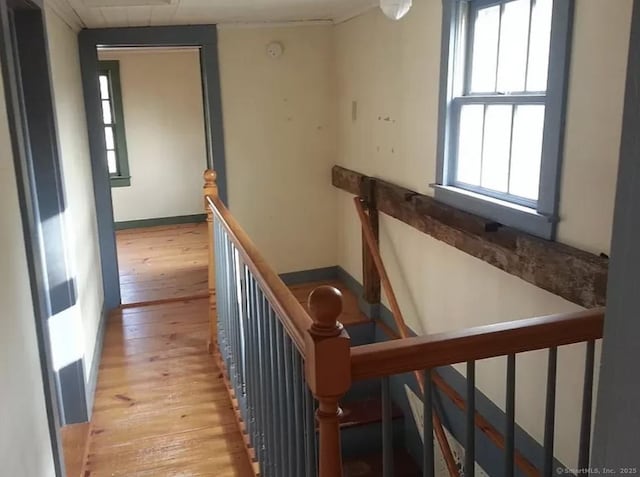 hallway featuring light wood-type flooring, baseboards, and an upstairs landing