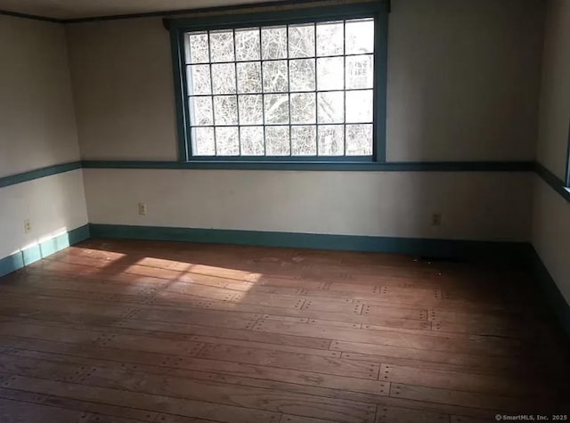 empty room with hardwood / wood-style flooring, baseboards, and a healthy amount of sunlight