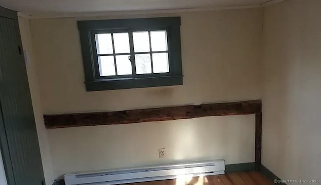 unfurnished room featuring a baseboard heating unit and wood finished floors