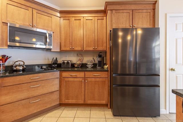 kitchen with light tile patterned floors, dark stone counters, and appliances with stainless steel finishes