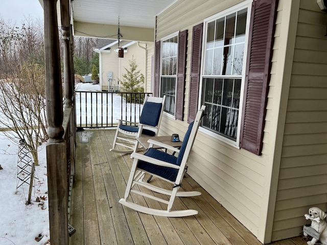 snow covered deck featuring covered porch