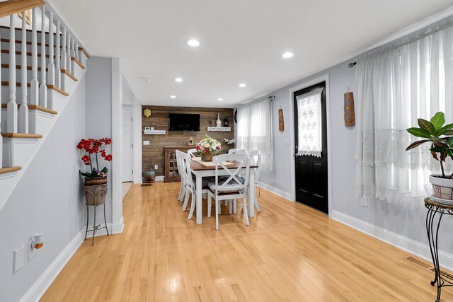 dining area featuring wooden walls and light wood-type flooring