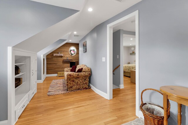 sitting room featuring lofted ceiling, wooden walls, and light hardwood / wood-style floors