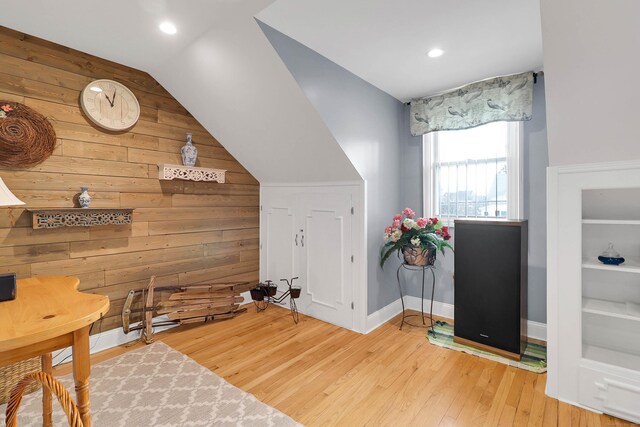 bonus room with hardwood / wood-style floors, wooden walls, and vaulted ceiling