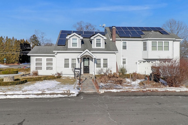 view of front facade featuring solar panels, a chimney, and roof with shingles