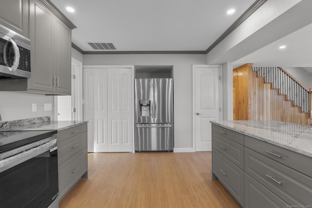 kitchen with stainless steel appliances, crown molding, gray cabinets, and light hardwood / wood-style flooring