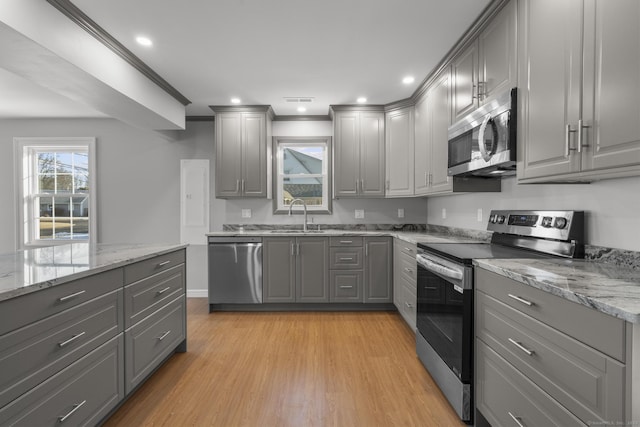 kitchen with light wood-type flooring, appliances with stainless steel finishes, sink, and gray cabinetry