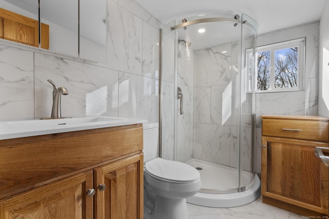 bathroom featuring vanity, tile walls, toilet, and walk in shower