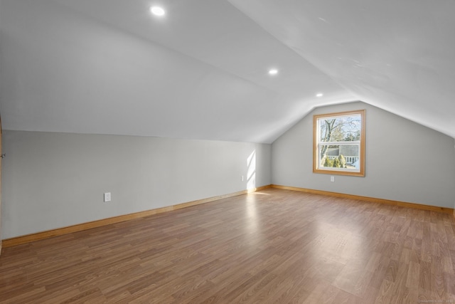 additional living space featuring vaulted ceiling and light wood-type flooring