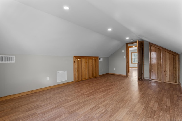 additional living space featuring lofted ceiling and light hardwood / wood-style flooring